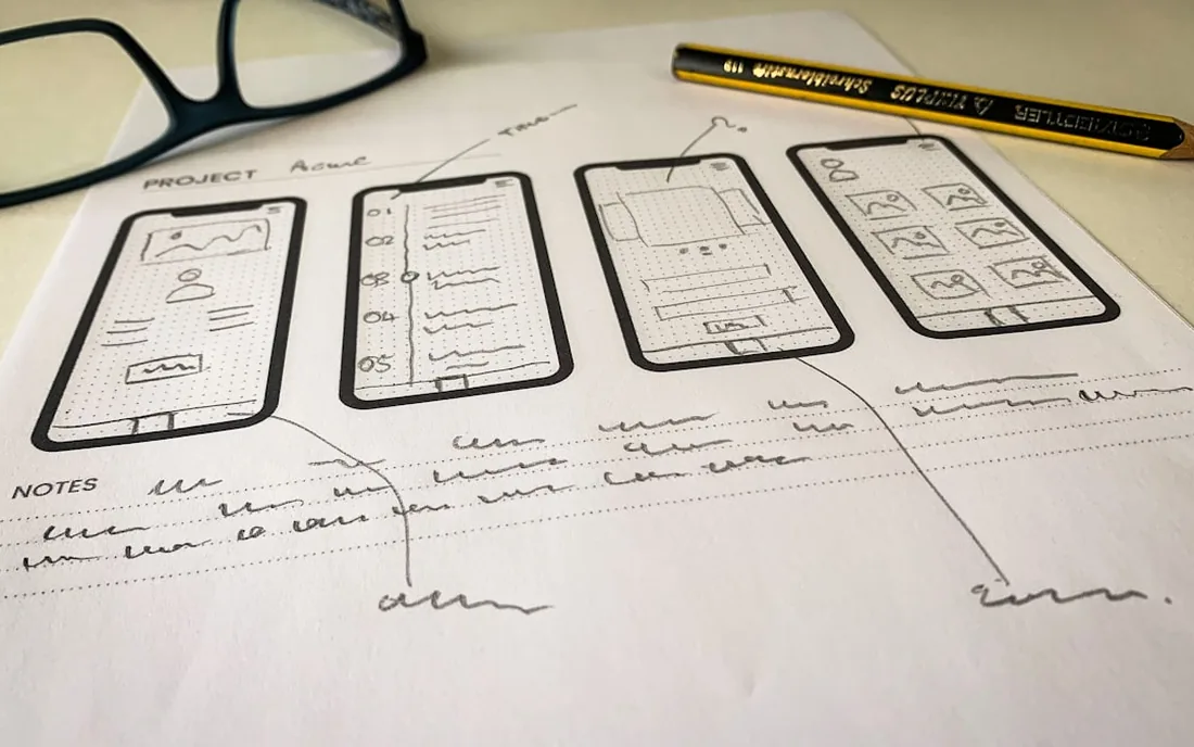 Phone-screen wireframes sketched on paper.
